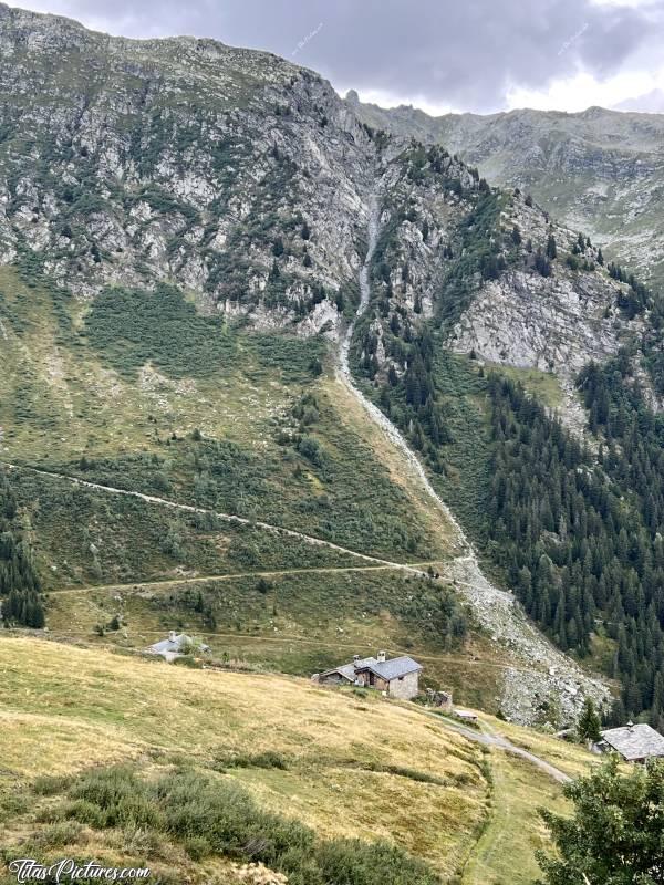 Photo Les Eucherts : Petite randonnée aux Eucherts, en direction du Plan de l’Arc. Ils paraissent tout petits ces chalets, devant cette grande masse rocheuse 🤭😅c, Tita’s Pictures, Les Eucherts, Montvalezan, les Alpes