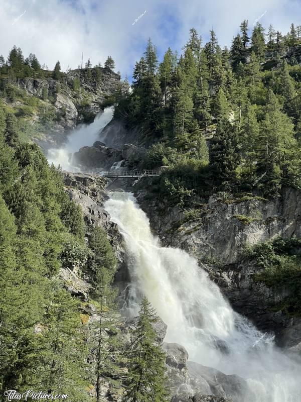 Photo Cascade du Ruthor : Ce petit pont sur la Cascade du Rutor, parait bien fragile face à la puissance de cette cascade 🤭😅c, Tita’s Pictures, Les Alpes, La Thuile, Cascade du Rutor, Randonnée, Torrente Ruthor, Sentiero Cascate del Rutor